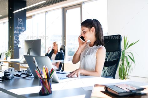 Two business women in the office working. by halfpoint. Two attractive young business women in the office working, one of them holding a smart phone, making a phone call.#working, #halfpoint, #attractive, #business Business Photoshoot, Accounting Firms, Accounting Services, Business Portrait, On The Phone, Business Loans, Business People, Branding Photoshoot, Working Woman