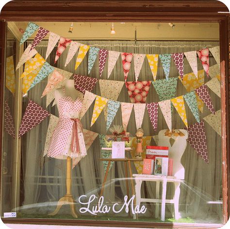 Paper garland gives a playful feel to this window display at Lulu Mae. #paper_inspiration #visual_merchandising Window Displays Retail Store Fronts, Gift Shop Display Ideas, Easter Store Window Display, Vintage Window Display, Spring Window Display, Store Front Windows, Window Display Retail, Decoration Vitrine, Summer Window