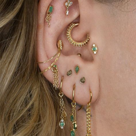 Introducing Solstice. This alluring threadless end features a 2mm Emerald and two Swarovski Crystals, creating a sleek and stunning design. Wear it solo or pair it with her charm companion to complete the look. Also available in a charm in Solstice Charm | Diamonds or in Swarovski Crystal in Solstice. Gold Aesthetic Ear Piercings, Ears Filled With Piercings, Gold And Emerald Earring Stack, Mixed Metal Ear Styling, Ear Piercing Themes, Stacking Earrings Ear Piercings, Maximalist Ear Stack, White Gold Ear Curation, Colorful Ear Stack