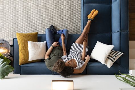 A bird-eye view of a couple relaxing on a blue corner sofa. L Shape Sofa Carpet Layout, Tv Room With L Shaped Sofa, L Shaped Sofa Layout, L Shaped Sofa Living Room Layout, Corner Sofa Living Room Layout, Sofa Cozy, Sofa Bed Furniture, Sofa Layout, L Sofas