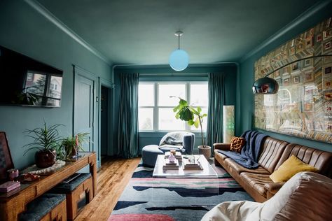 Blue pendant turned on in blue hued living room with large quilt hung above brown leather sofa in light filled room. Eclectic Vintage Bedroom, Mid Century Modern Leather Sofa, Floor Ottoman, Couch Accessories, Chicago House, Modern Leather Sofa, Hay Design, Modern Color Palette, Modern Pillows