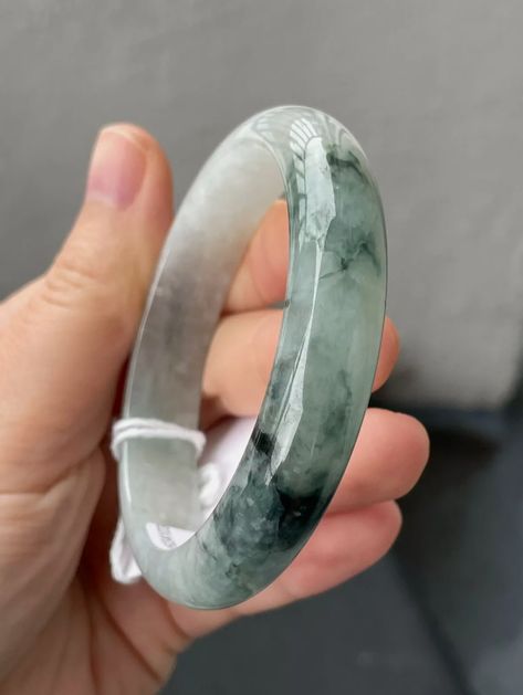 Hand holding a 58 mm Burmese Grade A jadeite bangle bracelet, featuring a smooth, glossy finish with natural green and white hues, showcasing the high-quality and untreated nature of the jadeite. Jade Bangle, My Jewellery, Jade, Bangles, Bracelet, Beauty