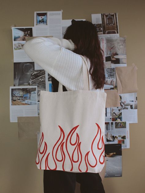 "Hand-painted \"flame\" design tote bag. A perfect accessory to spice up an everyday outfit. DETAILS: 16\" H x 15\" W x 21\" Handle and 3\" Gusset Like this item? Check out our website: https://www.dzaehelladreams.com/" Gift For Her Ideas, Tod Bag, Diy Bag Painting, Diy Tote Bag Design, Handpainted Tote, Painted Canvas Bags, Handpainted Tote Bags, Desain Tote Bag, Totes Ideas