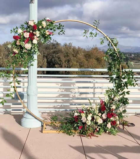 Circle arch filled with gorgeous fall flowers for a wedding at the Natural History Museum in San Diego's iconic Balboa Park by wedding florist Le Champagne Projects. Want to learn how to choose what ceremony design is best for you? Click the link for suggestions. #weddingflowers #ceremonyflowers #ceremonyarchideas #roundarchflowers #roundweddingarch #circleweddingarch #circleweddingarchflowers #sandiegoweddingflorist Wedding Arch Half Circle, Fall Wedding Circle Arch Flowers, Flowers On Circle Arch, Circle Arbor Wedding Flowers, Circle Arch Wedding Flowers, Circle Arch Decoration Wedding, Circular Arbor Wedding, Circle Arch Wedding Draping, Circle Alter Wedding