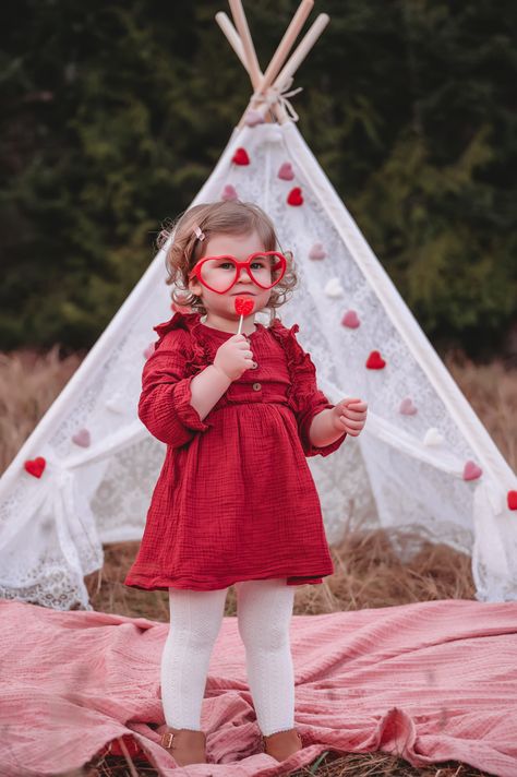 Valentine's Day mini session with toddler standing in front of lace tent covered in felt hearts, holding lollipop, wearing red dress and heart shaped glasses. February Mini Session Ideas, Boho Valentine’s Day Mini Session, Valentine Mini Session Outdoor, Valentines Day Mini Session Outdoors, Valentines Mini Session Ideas, Valentine’s Day Mini Session, Valentine Minis, Photography Space, Valentine Mini Session