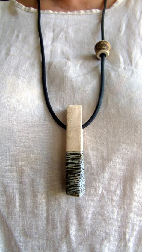 A long ceramic necklace with a geometric pendant for everyday wear. MATERIALS AND DIMENSIONS: The necklace is made of white clay, ceramic dyes, black rubber cord, without a clasp, connected to a tube of melchior. Baked at 1080 degrees Lightweight and comfortable to wear The ceramic pendant measures 1.5 x 9 x 1.5 cm Cord length: 73 cm. If you prefer a different length, feel free to contact me with your request. CONDITION OF PRODUCTS Each piece is unique. The artistic look of the creation is achieved through a particular hand-crafting process. Any imperfections are to be considered a feature, not a flaw. Ceramic Necklace Pendant, Ceramic Jewelry Design, Ceramic Bead Jewelry, Ceramic Pendant Necklace, Pebble Jewelry, Handmade Ceramic Jewelry, Micro Mosaic Jewelry, Boho Hippie Style, Hippie Stil