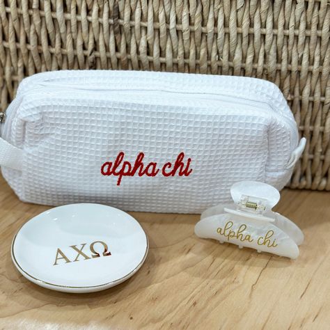 Select your assortment of Alpha Chi Omega gifts to make your own gift set! We'll package in a cellophane bag tied with ribbon in the sorority colors! Choose any combination of the these popular items, including the super trendy waffle weave bag, ring/pin dish with gold trim and the fun sorority embellished hair clip.  BAG: * 7.75" x 3.5" x 2.5" OR 7" x 4.75" x 3.5" * Poly/cotton waffle weave fabric exterior * Vinyl lined interior and one interior pocket RING/PIN DISH: This ceramic dish is 4" x 4" white ceramic porcelain with gold Greek letters. HAIR CLIP: 3-1/4" wide x 2.5" tall with heavy-duty claw design Personalized in high-quality printed vinyl on ONE side of the clip. ~ OTHER INFORMATION ~ Normal turnaround varies by item and is indicated in the shipping information. See shop announce Alpha Phi Baskets, Sorority Merch Sets, Sorority Gift Ideas, Big Little Basket Theme, Sorority Gift Baskets, Big Little Baskets, Sorority Big Little Baskets, Axo Merch, Sorority Little Gifts