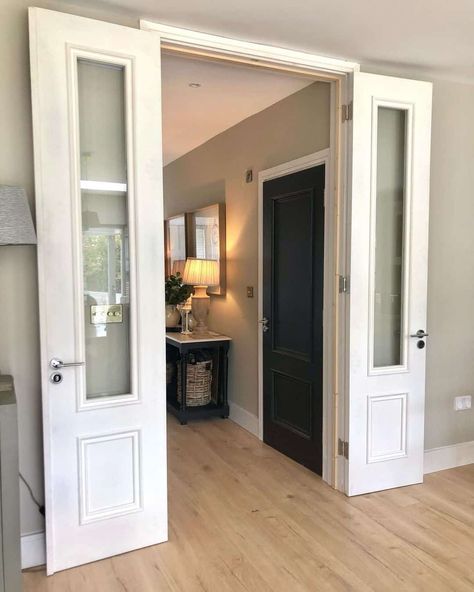 White double doors with glass are opened to reveal a hallway with light wood flooring. A two-toned black console table lit by recessed lights in the hallway stands next to a black interior door. Hallway Recessed Lighting, Doors In Hallway, White Double Doors, Light Wood Flooring, Black Interior Door, Black Sconces, Narrow Living Room, Recessed Lights, Black Console Table