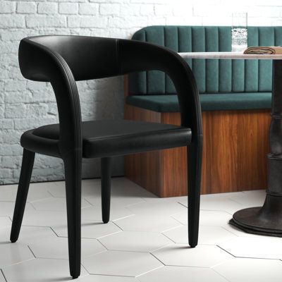 This contemporary dining chair has a sculptural silhouette that we’re quite taken with. Its curvaceous shape is sleek, elegant, a bit edgy – and most definitely distinctive. The rounded legs are angled open back that wraps around like arms, and the seat is padded with foam and wrapped in faux leather in the colour of your choice. Pull this chair up to your desk or consider a set to surround your dining or conference room table. No assembly is required, so you can enjoy it upon receipt. Colour: B Black Wood Chairs Dining Rooms, Barrel Chair Dining Room, Dinning Chairs Modern Luxury 2023, Black Modern Dining Chairs, Modern Black Dining Chairs, Curved Back Dining Chair, Black Upholstered Dining Chairs, White Dining Room Sets, Black Dining Room Furniture