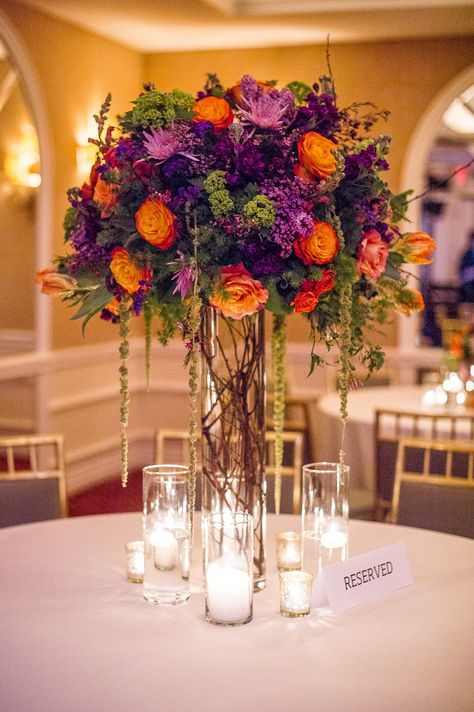 Purple and orange fall arrangement. Branching Out Floral & Event Design Photography: Amy Herfurth Photography - www.amyherfurth.com  Read More: http://www.stylemepretty.com/texas-weddings/2014/01/15/colorful-rosewood-turtlecreek-mansion-wedding/ Purple Wedding Centerpieces, Fall Purple, Tall Wedding Centerpieces, Boda Mexicana, Fall Wedding Centerpieces, Wedding Table Flowers, Floral Event Design, Tall Vase, Fall Wedding Flowers