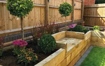 How to Build a Raised Garden Bed with Timber Railway Sleepers | Suregreen's Guide to Raised Beds Raised Garden Beds Along Fence With Seat, Sleeper Beds With Seating, Raised Garden Beds Sleepers, Garden Sleeper Planters, Garden Sleeper Ideas Raised Beds, Timber Sleepers Landscaping, Garden Bed With Seating, Diy Raised Garden Bed Along Fence, Raised Garden Beds With Bench