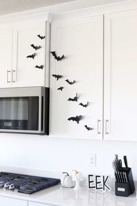 paper bats on kitchen cabinets in a white kitchen Paper Bats On Walls, Behind Tv Decor, Bats Halloween Decorations, Cheap Halloween Decor, Mirror Fireplace, Easy Halloween Decor, Paper Bats, Bat Display, Pumpkin Decorating Diy