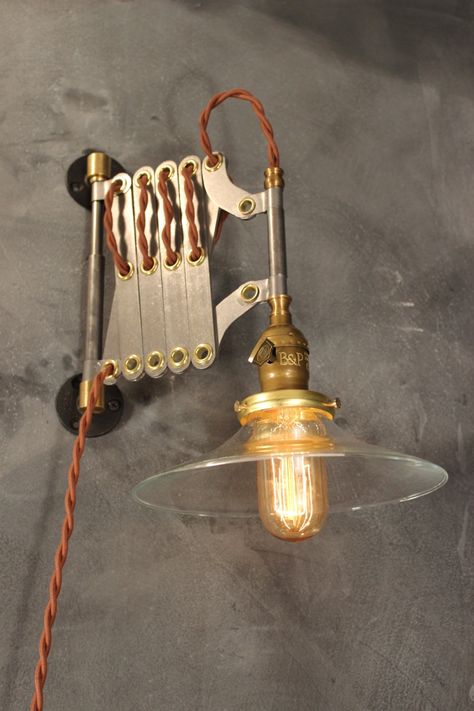 "Scissor sconces of various designs have hovered over many a workbench and drafting table throughout the last hundred years. Ours is based on the originals from the 1930s. Constructed of durable solid steel with brass hollow rivets and cast iron wall mounts. Comes wired with an antique style lamp socket, 9 feet of twisted cloth cord, and an industrial wall plug. (Cord color shown is Vintage Brown). The scissor arm opens and closes freely, and features three points of adjustment: horizontal swive Vs Wallet, Industrial Lighting Ideas, Industrial Lighting Design, Lampe Metal, Industrial Apartment, Vintage Industrial Lighting, Diy Lampe, Lamps Shades, Industrial Style Lighting