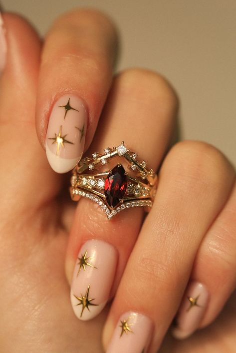 A woman's hand wearing a custom 3-piece wedding ring set from Staghead Designs. This 14K yellow gold ring set features an engagement ring with a marquise cut garnet center stone with claw prongs & round diamond accents & two contoured bands. The top band is V-shaped with princess cut diamonds that look celestial or like stars across the sky. The bottom band is V-shaped with pavé diamonds. This fully customizable set can also be made in 14K white or rose gold. Engagement Rings With Matching Band, 3 Part Wedding Ring, Green Sapphire Engagement Ring Marquise, Vintage Ruby Wedding Rings, Unique Ring Sets, Ruby Bridal Set, No Traditional Wedding Rings, Garnet Marquise Ring, Vintage Color Engagement Rings