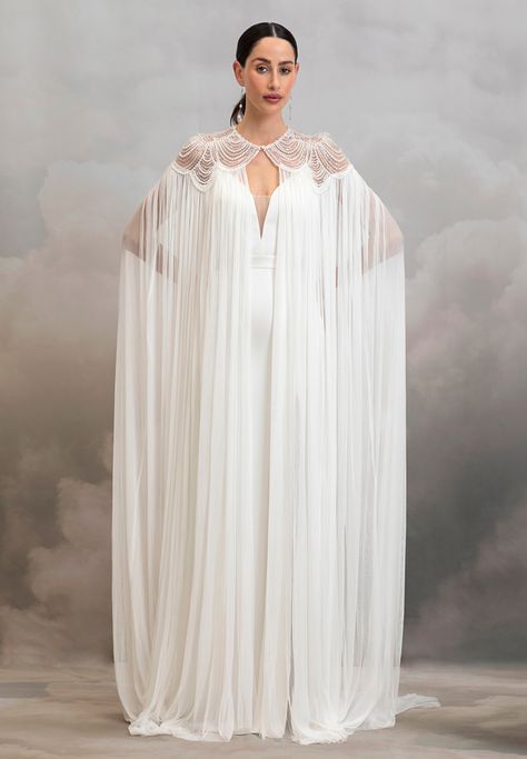 Add instant glamour to your bridal look with the dramatic Aster Cape. Pearl scalloped tulle embrace the neckline and shoulders of this whimsical cape before it drapes down in the softest 100% silk tulle. We suggest pairing this piece with a classic wedding gown or a topper and silky bridal trouser set to instantly elev Star Wars Wedding Dress, Classic Wedding Gown, Silk Wedding Gown, Wedding Cloak, Catherine Deane, Fantasy Outfits, Cape Gown, Cape Wedding Dress, Simple Gowns