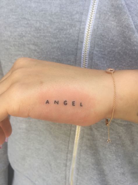 Angel Words Tattoo, Horizontal Hip Tattoo, Tattoo Between Boop Simple, Angel Tattoo Letters, Word Angel Tattoo, Mini Angel Tattoo, Angel Tattoo Writing, Angel Writing Tattoo, Angel Lettering Tattoo