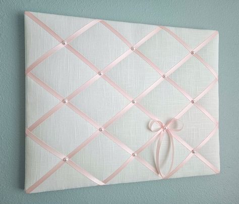 This delicate memo board in white linen fabric is accented with light pink satin ribbon and faux pearl details. Use it to display your photos, notes and cards, or just on its own as one of a kind soft wall hanging. Sizes: 20in wide x 16in tall (pictured) 24in wide x 18in tall 24in wide x 20in tall **Other sizes available, please contact me for details.** My memo boards and fabric pictures are carefully handcrafted using high quality materials, with generous batting. All my boards are light weigh Fabric Photo Board, Cork Board Covered In Fabric, Memo Board Diy, Fabric Pin Boards, Pin Board Ideas, Pink Linen Fabric, Bow Trend, Pink Dorm, White Linen Fabric