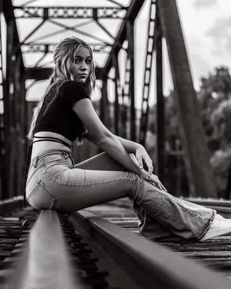 Black and white. Railroad bridge. Jeans and a black half shirt. Blonde girl sitting on railroad bridge. Photoshoot Railroad Tracks, Poses On Railroad Tracks, Photoshoot On Railway Track, Senior Pics On Train Tracks, Senior Picture Ideas On Railroad Tracks, Railroad Graduation Pictures, Female Senior Picture Poses Photo Ideas, Railroad Track Photoshoot Senior Pics, Cute Senior Photoshoot Ideas