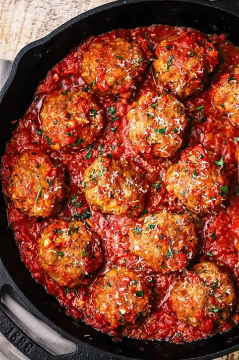 An overhead view of a large cast-iron skillet filled with Italian meatballs resting in a layer of homemade marinara sauce. Marinara And Meatballs, Mary Berg Taco Meatball Skillet, Creamy Tomato Meatballs, Light And Fluffy Meatballs, Meatball Sandwiches Recipes, Skillet Meatballs In Marinara, Meatballs Cast Iron Skillet, Beef Italian Meatballs, Sweet Italian Meatballs