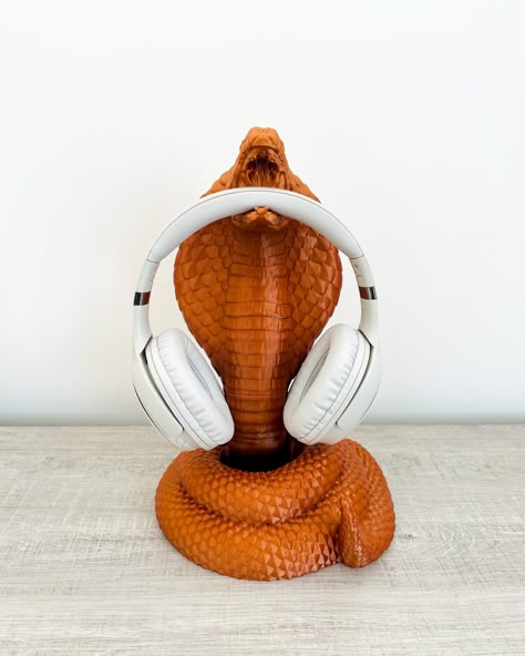 King Cobra Headphone Stand - Elegance and Functionality for Gamers! 🐍🎮 Elevate your gaming experience with the King Cobra Headphone Holder! This unique headphone stand not only elegantly showcases your headphones but also adds an exotic charm to your space. Crafted with meticulous attention to detail, it is designed to cradle your headphones with the grace of a king cobra. The product is expertly crafted using eco-friendly plant-based plastics through 3D printing technology. Exotic Elegance: T Headphone Stand 3d Printed, Headphones Stand, Ceramic Monsters, Plastic Gift Wrap, Headset Holder, Headset Stand, Headphone Stand, Headphone Holder, 3d Printed Objects