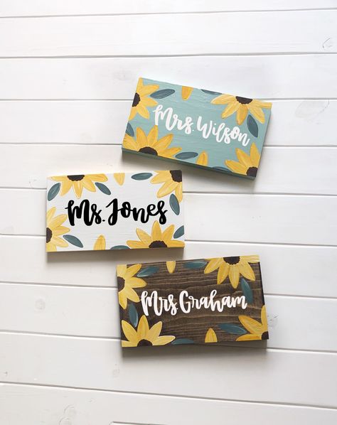 "Sunflower Teacher Name Sign  Cute to sit on a desk or shelf (can stand alone) or request to have a twine hanger attached to hang the sign on a hook or doorknob  Hand lettered name- hand painted flowers No two signs are exactly alike! No stencils used  Wooden sign measures approximately 5.5 by 10 by 1 inches  If you have a longer name, you can order this \"add on\" listing to make it 14 inches long instead of 10 inches long. Message me with any questions. Link,  https://etsy.me/2SJ67K4   Choose Sunflower Classroom, Painted Name Signs, Teacher Desk Signs, Teacher Classroom Sign, Teacher Door Sign, Teacher Canvas, Teacher Door Signs, Teacher Door Hangers, Teacher Name Signs