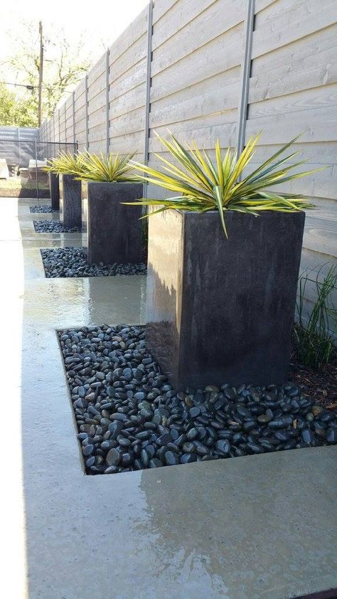 Mexican River Rock, Front Yard Landscaping Modern Design, Minimal Outdoor Landscaping, Driveway Rock Landscaping, Black Stone Landscaping Modern, Modern Side Yard Landscaping, Modern Flowerbed Ideas, Cement Front Yard Ideas, Planters In Rock Beds