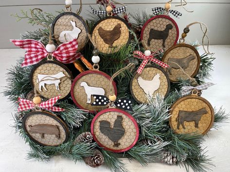 "Farmhouse Christmas Ornaments.  Embellished Wood Christmas Ornaments of Farm Livestock Animals.  These Animal Ornaments can be finished off with either a wood bead and bow or a couple of wood beads.  Farm Animal Ornaments are: Rabbit Ornament Laying Hen on a Nest Ornament Standing Hen Ornament Rooster Ornament Heifer Ornament Steer Ornament Goat Ornament Lamb Ornament Pig Ornaments These Farm Ornaments are 2-dimensional that are laser cut on baltic birch and are finished on both sides.  The wood background is an engraved mock chicken wire and the animals are wood cutouts attached to the background and encased in a wooden circular frame.   If you would like a plain ornament (no ribbons or beads) we offer those in another listing:   https://www.etsy.com/listing/1067705077   Each ornament is Wooden Farmhouse Christmas Tree Ornaments, Country Christmas Trees Ornaments, Home Made Christmas Ornaments Farmhouse, Rustic Farmhouse Christmas Tree Ornaments, Christmas Tree Farmhouse Ornaments, Home Made Rustic Christmas Ornaments, Farm Animal Ornaments, Farm Ornaments, Livestock Animals