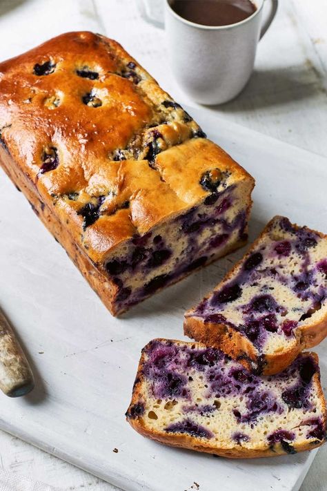 Cake cut into two slices showing blueberries inside sat on a white chopping board surrounded by a knife and a mug of tea Blueberry Lemon Yoghurt Cake, Yoghurt Loaf Cake, Blueberry Yoghurt Cake, Blueberry Cake Healthy, Healthy Loaf Cake, Healthy Yogurt Cake, Lemon And Blueberry Cake, Blueberry Loaf Cake, Blueberry Yogurt Cake