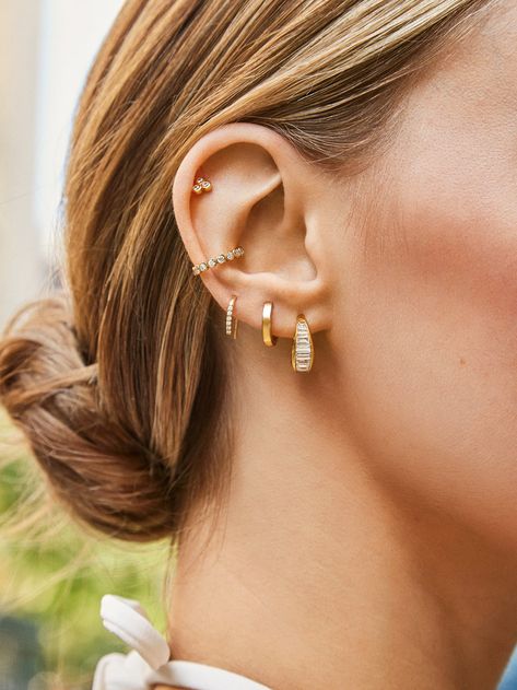 We were dreaming of a pair of chunky hoops with baguette stones, so we made that happen with the Tina 18K Gold Earrings. Crafted from 18K gold plated sterling silver, these contemporary hoops incorporate sleek east-west Cubic Zirconia stones to give this style just the right amount of edge. Styling Triple Lobe Piercings, Ear Piercings Helix Stud Cartilage Jewelry, Top Of Ear Piercing Ideas, Piercings That Go With Conch, Pinterest Ear Piercing, Piercing Styling Ideas, Earrings 4 Holes, Earring Stack Inspiration, Huggie Earring Stack