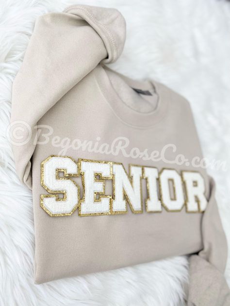 This cozy chenille patch SENIOR sweatshirt is the perfect crewneck sweatshirt to give for your favorite senior in the class of 2025!   It is a great end of school year gift, graduation gift, summer sweatshirt or gift for her. The sweatshirt is the Gildan brand unisex sizing.  They run true to size so if you'd like a baggy sweatshirt we recommend sizing up.  It is crewneck, long sleeve and has elastic at the sleeve cuff and bottom waistband. We offer 4 sweatshirt colors (white, grey, sand, and black) and 2 patch colors (light pink and cream white).  Colors may appear slightly different in person versus on the computer screen and our photos all show natural lighting. The patches are heat pressed on and all designs are hand placed, therefore there may be a slight difference in positioning of Senior Year Things, Senior Class Shirts, Senior Sweatshirts, Senior Year Fun, Senior 2023, Summer Sweatshirt, Class Shirt, Chenille Patch, Senior Shirts