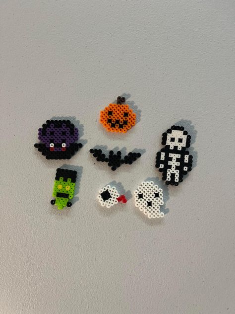 These are keychain sized Halloween designs made of Perler beads. Melt Beads Patterns Halloween, Halloween Perler Beads 3d, What To Do With Perler Bead Creations, Perler Bead Pants Chain, Melty Bead Halloween, Halloween Perler Bead Patterns Pumpkins, Music Note Perler Beads, Perler Beads Cats, Iron Beads Halloween