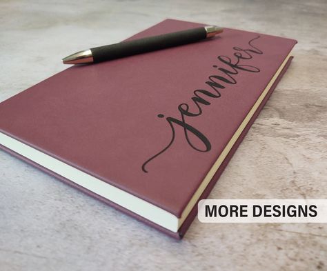 "Personalized Journal - 5 1/4\" x 8 1/4\"  x 3/4\" Engraving will be black on all colors except RUSTIC BROWN and BLACK (2 options) - Rustic Brown engraves to Gold - Black engraves to Silver or Gold  - Blue engraves to Silver Custom requests are welcome and more design options available here https://www.etsy.com/shop/EventCityDesign?ref=seller-platform-mcnav&section_id=22591708 ORDERING Please select the design number and enter the exact details for the engraving in the notes box or send us a mes Personalized Journal Cover, Personalized Journals, Bookmark Pen, Cricut Projects Easy, Soft Cover Journal, Memory Journal, Design Number, Life Journal, Ribbon Bookmarks