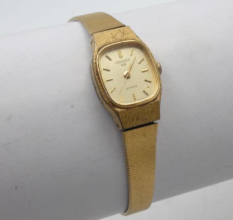 "Beautiful and sleek vintage womans wristwatch. Metal case with quartz analog dial Gold tone band with clasp connection safety chain. 7\" long Good condition with mild wear. Fully serviced and working great with a new battery installed. VX Quartz Orient Watch Co Japan Your watch will be shipped safely in a custom gift box suitable for presentation.  Deck Vintage strives on being a source for authentic vintage and historic items in the best condition possible. Any flaws or wear will be visible in photos, any significant or hard to see flaws will be mentioned in description. All watches are cleaned, serviced when needed, fully tested and shipped with new battery installed.. Feel free to message me for any questions you may have, I'm easy to talk to. Although your item will be mindfully packa Luxury Vintage Brown Watch, Luxury Vintage Brown Watch Accessories, Orient Watch Vintage, Vintage Gold Watch, Tone Art, Presentation Deck, Orient Watch, Ring Bands, Gold Watches Women