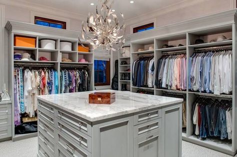 Walk-in closet with open cubbies over clothes rails centered on a gray closet island accented with crystal pulls and a white marble counter illuminated by a modern silver chandelier. Closet Chandelier, Gray Closet, Transitional Closet, Organiser Son Dressing, Master Closet Design, Closet Island, Closet Planning, Walk In Closet Design, Open Closet