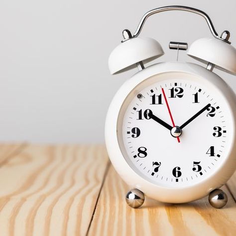 Small white alarm clock, black numbers, set the time for 10.10 o'clock, placed on a wood table. Small Clock, Black Numbers, Angel Number Meanings, Meditation Mantras, Spiritual Coach, Number Meanings, Clear Mind, Wooden Desk, Table Clock