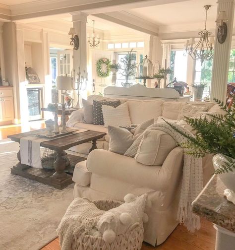 The relaxed, lived-in look of this cozy French cottage living room is awe-inspiring. Filled with plush pillows and linens that are centered on comfort, elegant touches like the antique sconces on the decorative pillars, and the various other French-inspired light fixtures fill this space with character. To achieve this look, select gentle faded neutrals to accompany whimsical yet robust furniture and you're on your way to fulfilling this ever-popular aesthetic. Cozy French Cottage, French Country Family Room, Farmhouse Living Room Designs, French Cottage Living Room, Country Cottage Living Room, Farmhouse Living Rooms, French Cottage Decor, Bungalow Interiors, Country Style Living Room