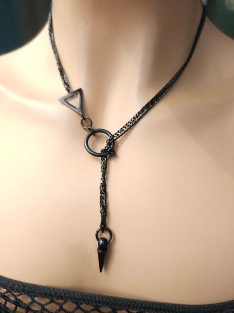 This is a bold and edgy blackened steel Lariat Goth Grunge Alt aesthetic Necklacevwrap choker with Spike pendant.  The minimalist design gives it a trendy and stylish feel, while the black steel gives it a touch of gothic Punk edge. This necklace is versatile, and can be worn long or doubled up for a layered look depending on what size you choose. Goth Jewelry Necklaces, Unique Jewelry Necklaces, Edgy Jewelry Aesthetic, Ring On Necklace Chain, Cool Chokers, Black Accessories Aesthetic, Goth Jewelry Aesthetic, Goth Jewelry Diy, Grunge Alt Aesthetic