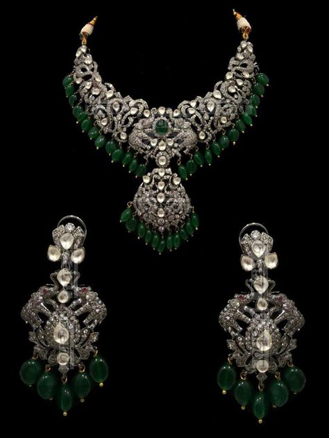 "Israh Victorian Emerald Bridal Set This traditional yet very trendy silver and kundan number is perfect for your wedding attire.This set features a choker style necklace with polki detailing. This Emeralds & Victorian setting stunning necklace set is made of copper+silver alloy with white kundan stones, which are covered in silver foil. The set has a stunning emerald pendant and matching earrings. The whole process is the traditional jadau process of making jewelry. Elevate your style quotient Victorian Style Necklace, Victorian Sets Jewellery, Victorian Antique Jewelry, Silver Victorian Jewelry, Victorian Diamond Jewellery, Victorian Gold Jewelry, Vintage Necklace Victorian, Victorian Polki Jewellery, Victorian Jewelry Indian