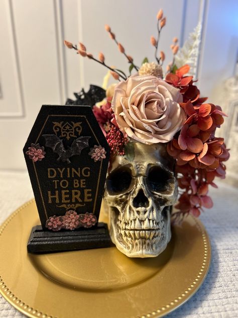 Skull floral arrangement. Pink, black and gold with a gorgeous skull centerpiece. Beautiful and elegant centerpiece. A unique hand painted coffin shaped sign will  add a small shabby chic gothic touch to any room. This skull and floral centerpiece is a perfect Halloween decoration, or Halloween wedding decor for that extra special touch. Totally shabby chic. Sizing/Dimensions 13 inches wide and 19 inches tall Features: Lightweight Durable  Gold base  Black, pink, white flowers This is the actual Gothic Candelabra Centerpiece, Spooky Table Centerpieces, Gothic Party Centerpieces, Glam Skull Decor, Goth Baby Shower Games, Witchy Centerpieces Wedding, Gothic Wedding Party Favors, 30th Birthday Rip 20s, Gothic Wedding Centerpieces Table Decor