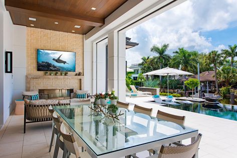 This lanai features a TV, fireplace, and dining table, all right next to a pool. Designed by MHK Architecture in Naples, Florida. Mhk Architecture, Tv Fireplace, Coastal Retreat, Naples Florida, Coastal Homes, A Tv, Naples, Luxury Living, Fireplace