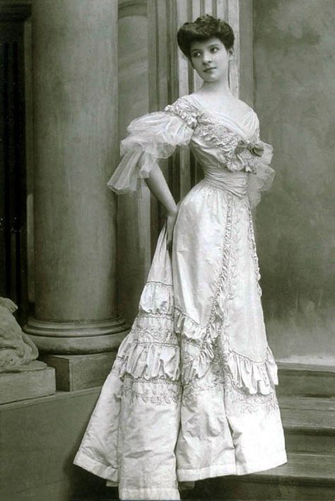 Evening gown, Worth, 1905. Bright floor-length dress in silk taffeta, tone on tone embroidered with rose pattern. The narrow, high waist is accented by an incorporated corset belt. Deep neckline bordered with draped tulle and accented with applied loop. Three-quarter-length sleeves are also made of draped and shirred tulle. Photo: Léopold-Émile Reutlinger. State Museum of Berlin