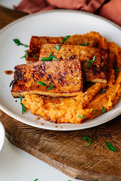 A smoky, savory tofu steak marinated before pan frying and laid on top of a bed of garlicky, herby mashed sweet potatoes. With extra umami marinade drizzled over top. The perfect 30-minute vegan dinner for weeknights! And an impressive main dish for a holiday table. Mashed Sweet Potatoes Vegan, Tofu Roast Dinner, Sweet Potato And Tofu, Tofu Thanksgiving Main Dish, Thanksgiving Tofu Marinade, Tofu And Potatoes, Vegan Dinner With Sweet Potatoes, Tofu And Mashed Potatoes, Savory Tofu Recipes