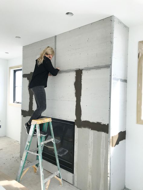 A DIY Concrete Fireplace That Cost Less Than $250 | domino Concrete Skim Coat Fireplace, Cement Fireplace Makeover, Symmetrical Living Room With Fireplace, Large Cased Openings Between Rooms, Fireplace Wall Finishes, Fireplace Trends For 2024, Dark Fireplace Ideas, Modern Boho Fireplace, Concrete Fireplace Diy