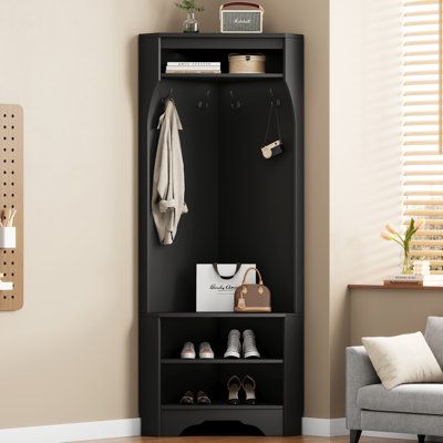 This contemporary corner hall tree is a perfect space-saving solution for your entryway, hallway, or living room, blending both modern style and practicality. Its streamlined design fits neatly into any corner, offering a shoe bench with adjustable shelves to store shoes or other essentials. The top storage shelf provides a place for hats, bags, or decorative accents, while the four sturdy hooks are ideal for hanging coats, bags, or scarves. The elegant skirting line detail adds a traditional aesthetic, maintaining a clean and organized look. This hall tree is the perfect combination of style and functionality, making the most of unused corner spaces. Latitude Run® Colour: Black | Latitude Run® Hall Tree 29.5" Wide w/ Bench And Shoe Storage Brown, Manufactured Wood | MLFE4313 | Wayfair Can Corner Coat And Shoe Storage, Corner Coat Rack And Bench, Coat Hooks Entryway Small Spaces, Corner Entryway Bench, Corner Coat Rack, Corner Hall Tree, Livng Room, Entryway Storage Cabinet, Current Aesthetic