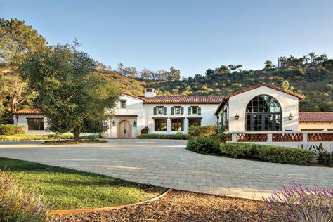 “This estate unfolds slowly from a long entry drive,” architect Christian Rice says of this Rancho Santa Fe primary residence, one of a number of structures newly built upon an undeveloped 7.75-acre lot. “You don’t really see it all until you’re right in front of it, which is a neat progression,” he adds. The façade features shutters inspired by European country homes that also nod to California’s early ranch home heritage. European Country Home, French Limestone Fireplace, Mediterranean Revival Style, Limestone Fireplace Surround, Ranch House Designs, Mediterranean Revival, Spanish Style Homes, Ranch Style Homes, Horse Ranch