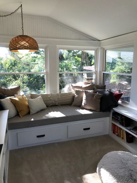 Bench with drawer storage and built-in shelves in sunroom. Wicker hanging lamp thrifted from a vintage store. Built In Bench Seating Sunroom, Built In Bench Sunroom, Couch In Sunroom, Bench Seating Conservatory, Window Seat Sunroom, Sunroom Built In Seating, Sunroom With Built In Benches, Built In Benches With Storage, Conservatory Storage Ideas