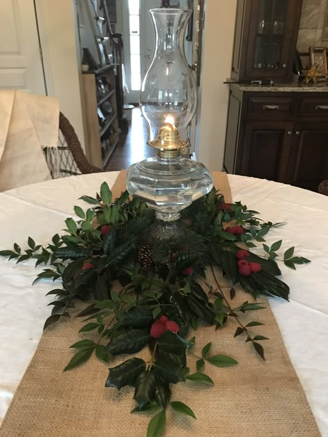 Oil lamp, fresh greenery Oil Lamps On Mantel, Oil Lamp Christmas Decor, Antique Oil Lamp Decor Ideas, Oil Lamp Centerpiece Wedding, Lamp Centerpieces, Oil Lamp Decor, Oil Lamp Centerpiece, Lamp Centerpiece, Bordeaux Wedding