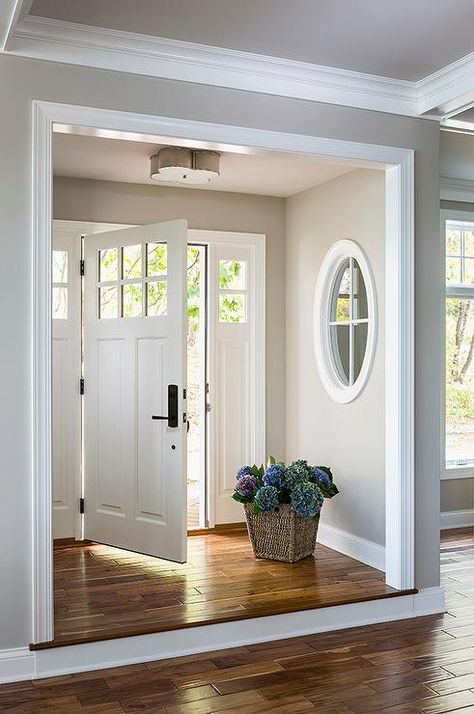 A step up leads to a foyer nook filled with walls painted gray framing a white paneled front door illuminated by a Basil Flush Mount. Ruang Tamu Outdoor, White Molding, Black Shutters, Farmhouse Front Door, Interior Windows, Friday Favorites, Front Door Design, Hus Inspiration, Black Doors