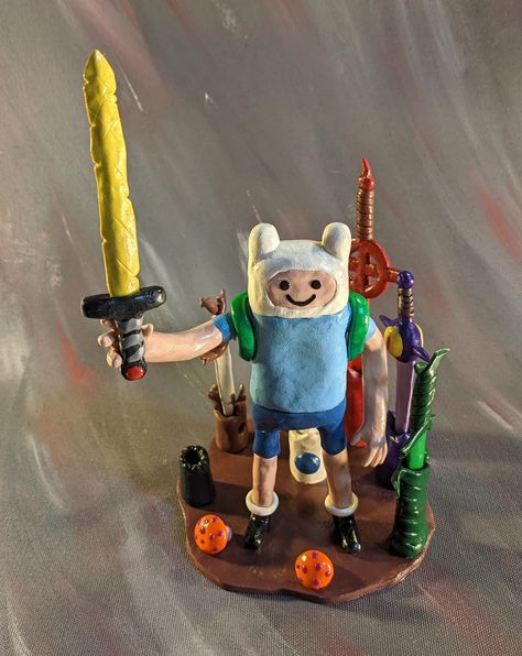 It's Adventure Time! Now you can have a handmade sculpture of Finn with 7 of his swords from the series that fit into his right hand with magnets. Finn stands on a clay base with an upright holder for each sword when not in his hand. This sculpture comes with 8 pieces (Finn on a stand and the 7 swords) handmade from polymer clay and magnets and then finished with glaze. Please note that this is a sculpture for display only and not a toy, as polymer clay can break. In the event that your sculptur Appa Clay Sculpture, Legend Of Zelda Clay Art, Adventure Time 3d Print, Adventure Time Air Dry Clay, Adventure Time Clay, Adventure Time Sculpture, Miraculous Ladybug Toys, Character Tropes, Adventure Time Cartoon