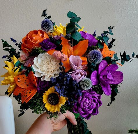 This beautiful sola wood flower bouquet features shades of purple, orange, yellow, and little pops of blue and pink.  Flowers are accented by real preserved eucalyptus and dried wildflowers. This bouquet is a classic bohemian wildflower style- perfect for your wedding or event!   Sunflowers and tigerlily might be our new favorite combo! Pictured bouquet is 10 inches in diameter.   Message me to customize. Eucalyptus And Wildflower Centerpiece, Purple Orange Yellow Wedding Flowers, Purple Blue Yellow Flower Arrangement, Purple And Yellow Flower Bouquet, Tigerlily Bouquet, Purple Prom Flowers, Purple And Orange Bouquet, Floral Arrangements Purple, Purple Yellow Wedding